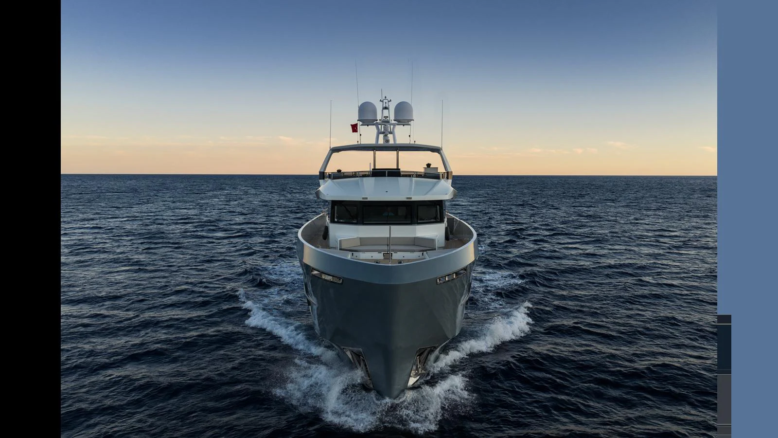 A sleek yacht cruises forward on calm waters under a serene sky. aboard Q.M Yacht for Sale