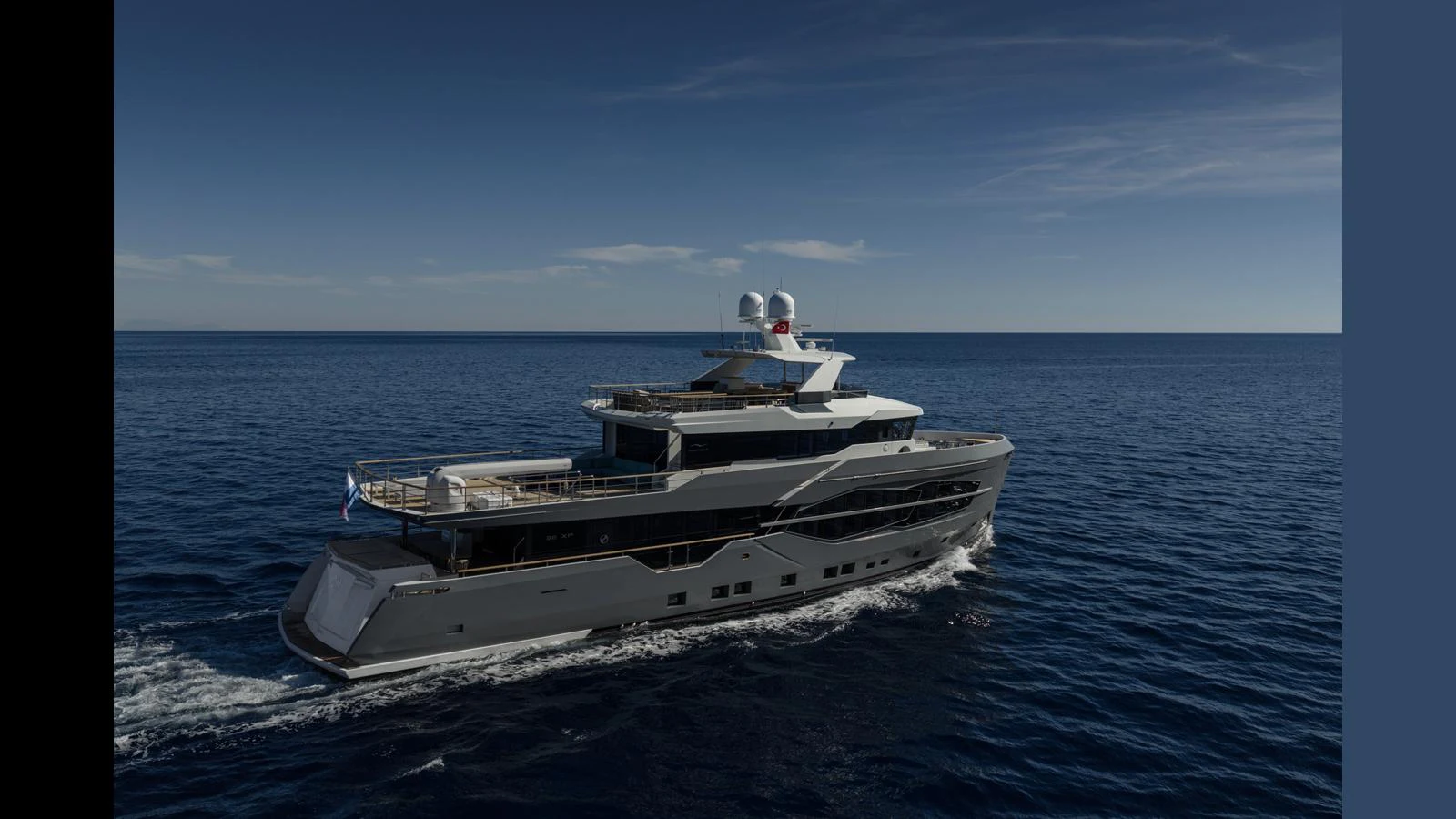 A sleek and modern yacht cruising on calm blue waters under a clear sky. aboard Q.M Yacht for Sale