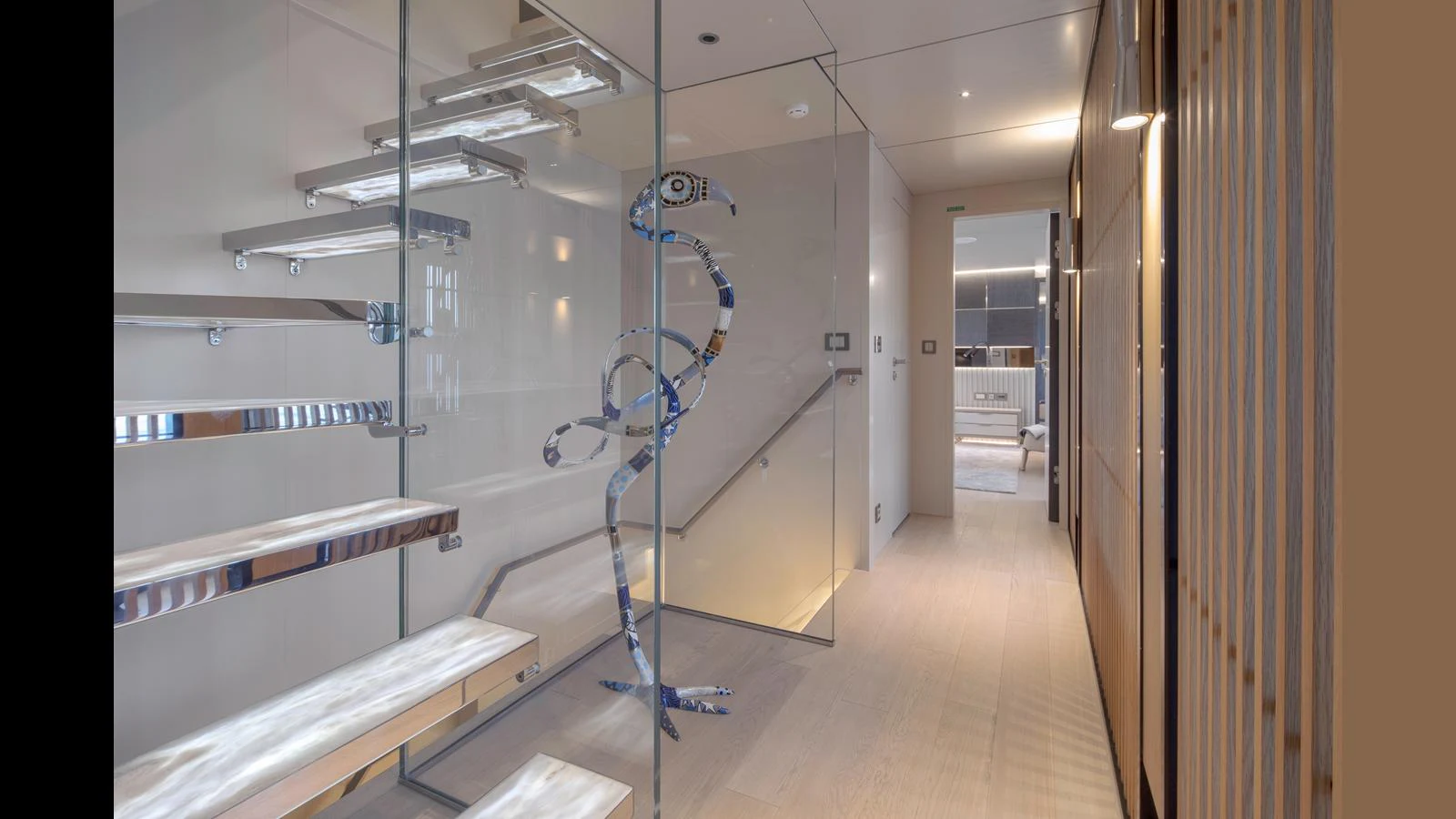 A modern yacht interior featuring a sleek glass and metal staircase with artistic elements. aboard Q.M Yacht for Sale