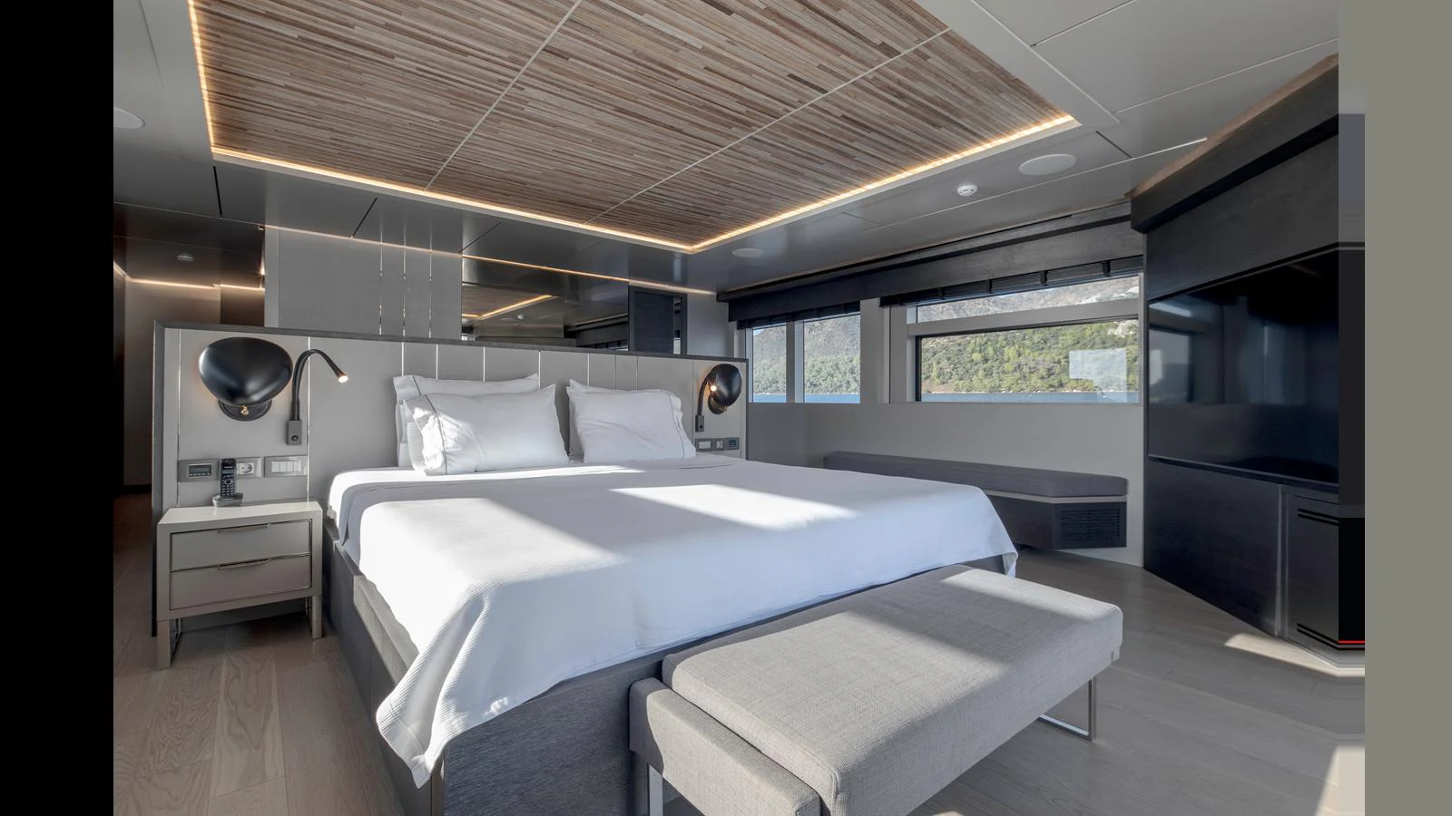 The master stateroom features a luxurious bed with modern lighting and ample natural light from large windows. aboard Q.M Yacht for Sale