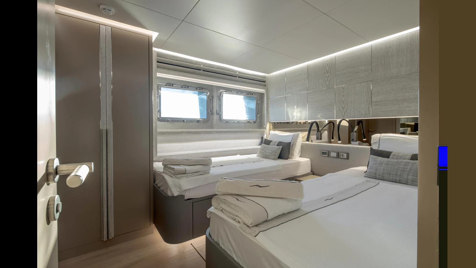 The guest stateroom features twin beds, modern decor, and ample natural light from the windows. aboard Q.M Yacht for Sale