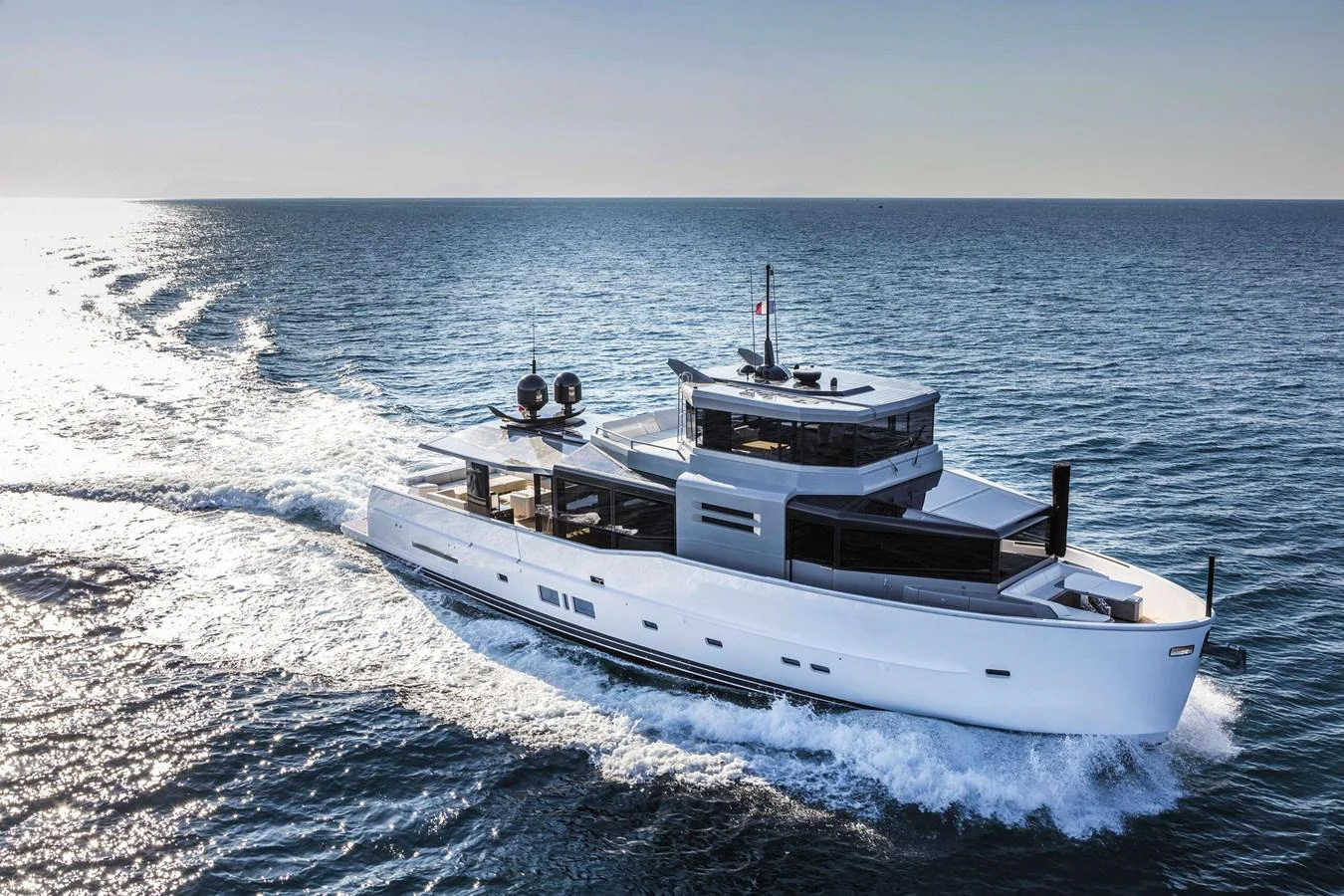 A sleek, modern yacht glides effortlessly across the open sea under a clear sky. aboard D&D Yacht for Sale