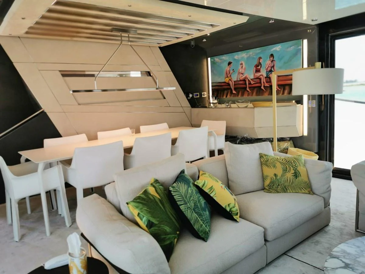 The salon features a comfortable seating area with tropical-themed cushions and a modern dining space. aboard D&D Yacht for Sale