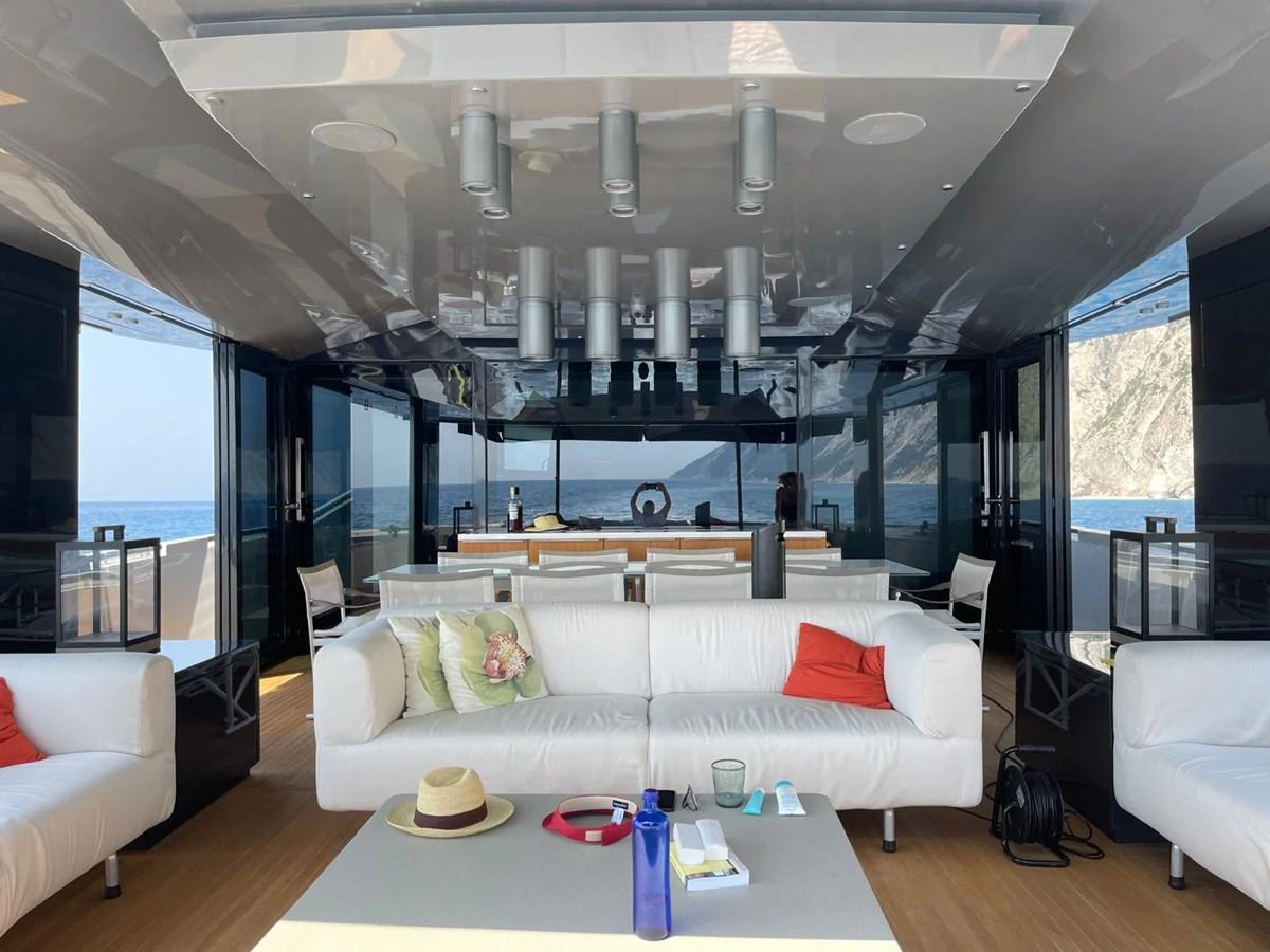 The salon features comfortable seating with a view of the ocean through large windows. aboard D&D Yacht for Sale