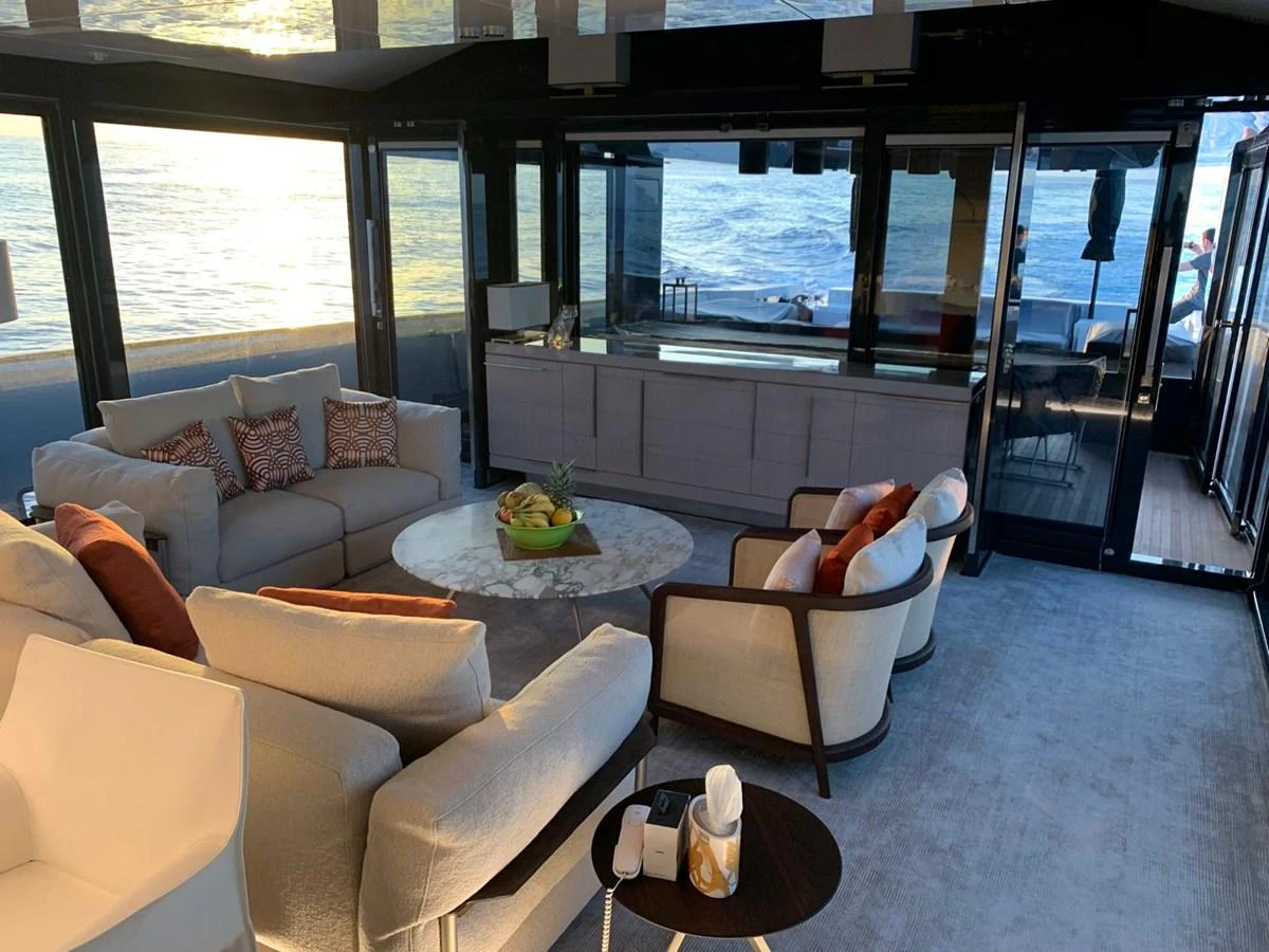 The yacht's interior features a luxurious seating area with panoramic ocean views through large windows. aboard D&D Yacht for Sale