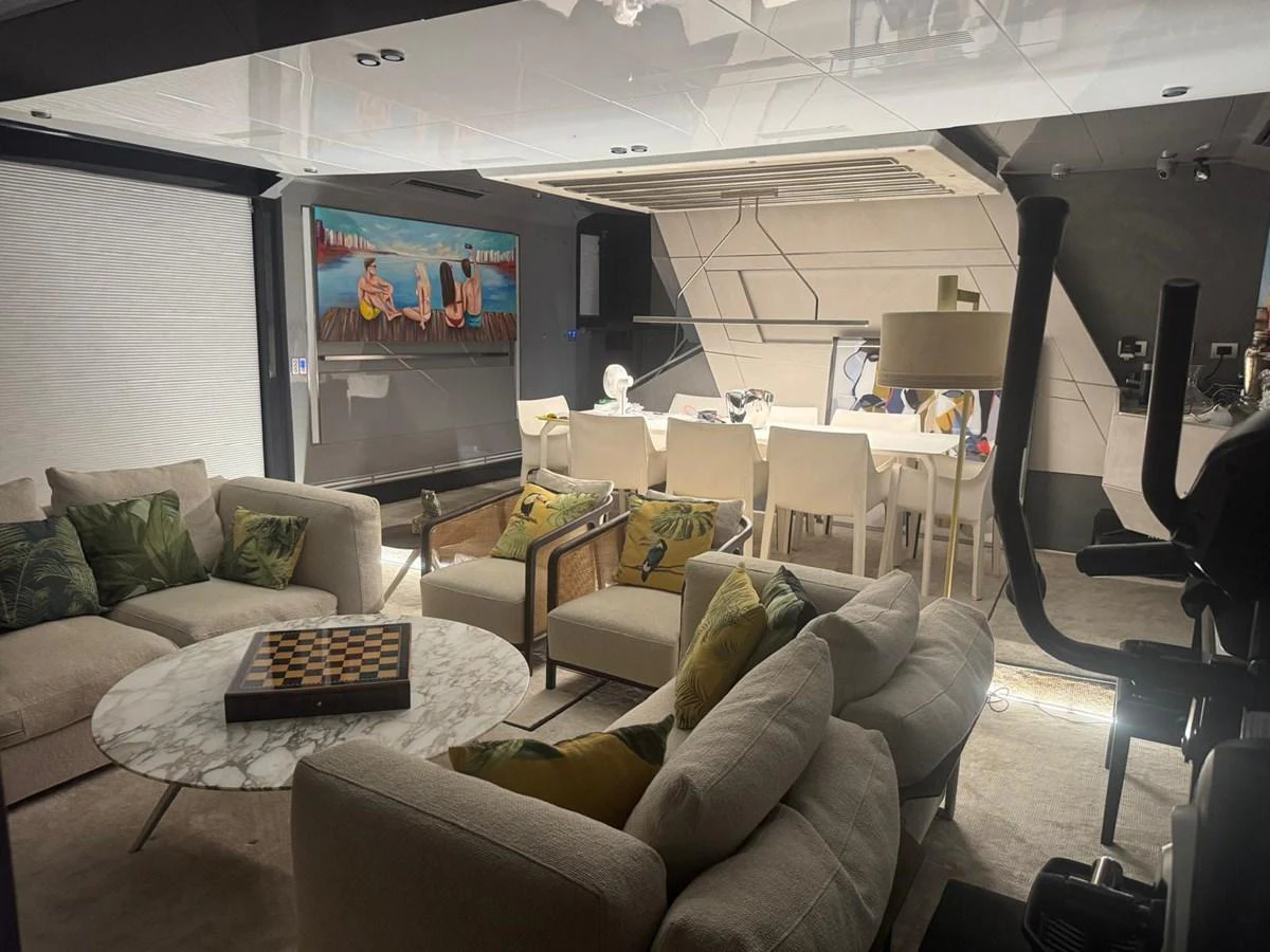 The yacht's salon features a cozy seating area with a chessboard, a dining table, and a large TV, creating a perfect space for relaxation and entertainment. aboard D&D Yacht for Sale