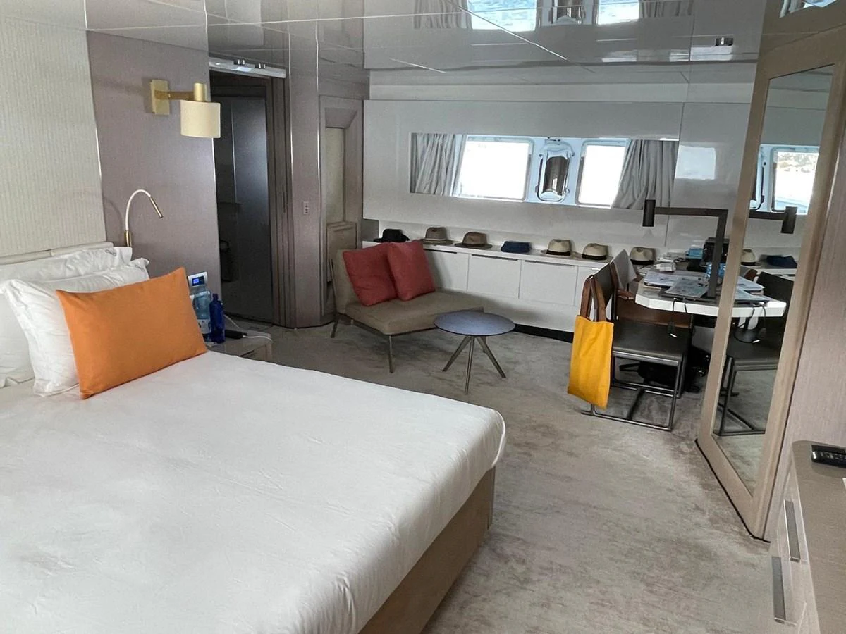 A luxurious stateroom featuring a comfortable bed, seating area, and ample natural light. aboard D&D Yacht for Sale