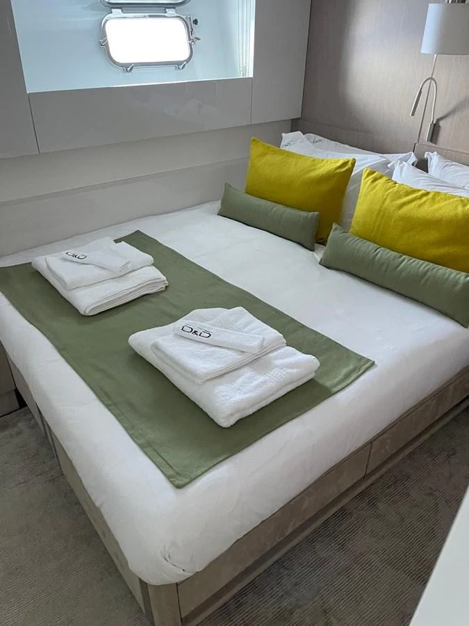 A cozy stateroom featuring a neatly made bed with green and yellow accents. aboard D&D Yacht for Sale
