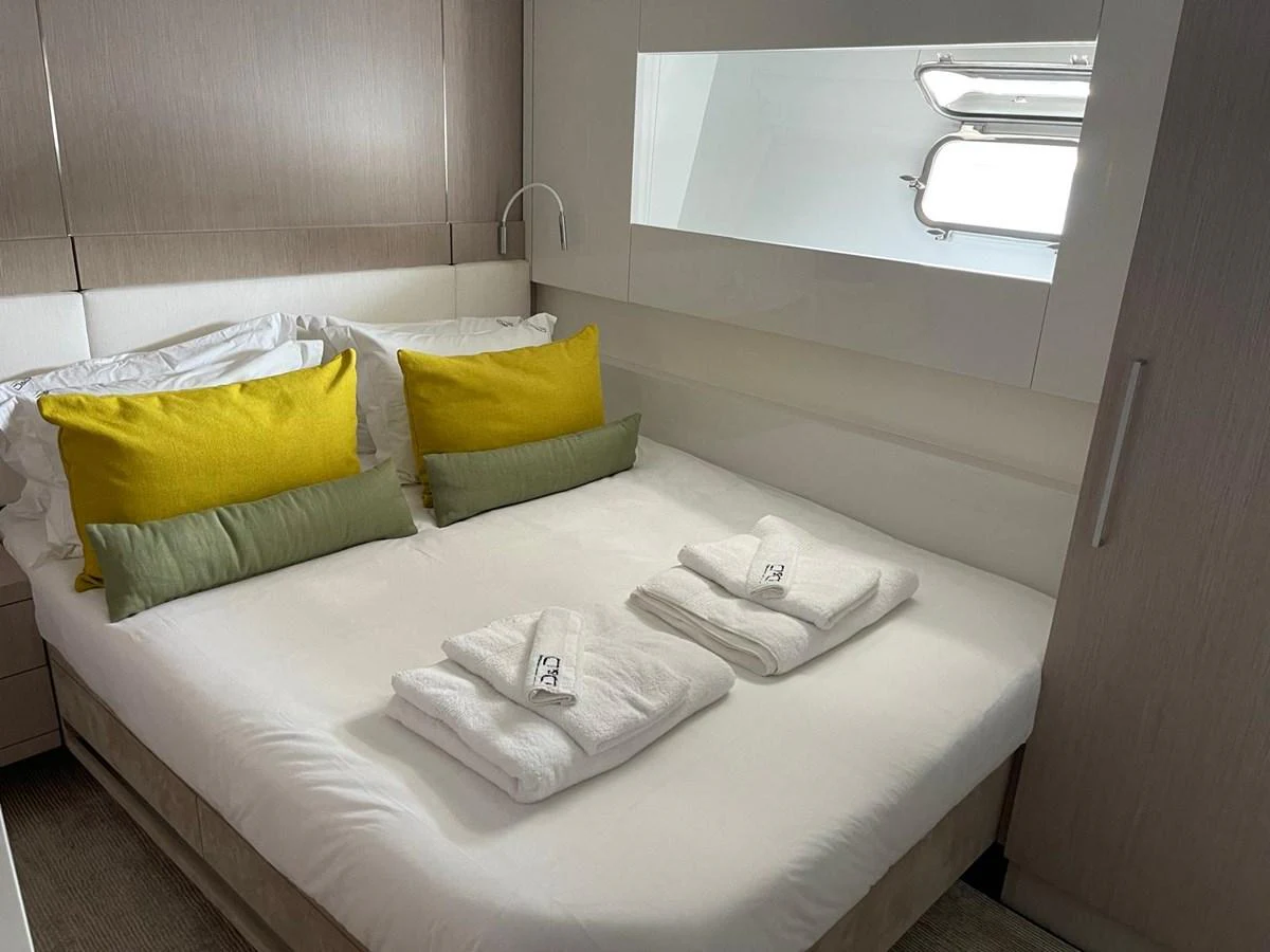 A cozy stateroom with a neatly made bed and bright accent pillows. aboard D&D Yacht for Sale