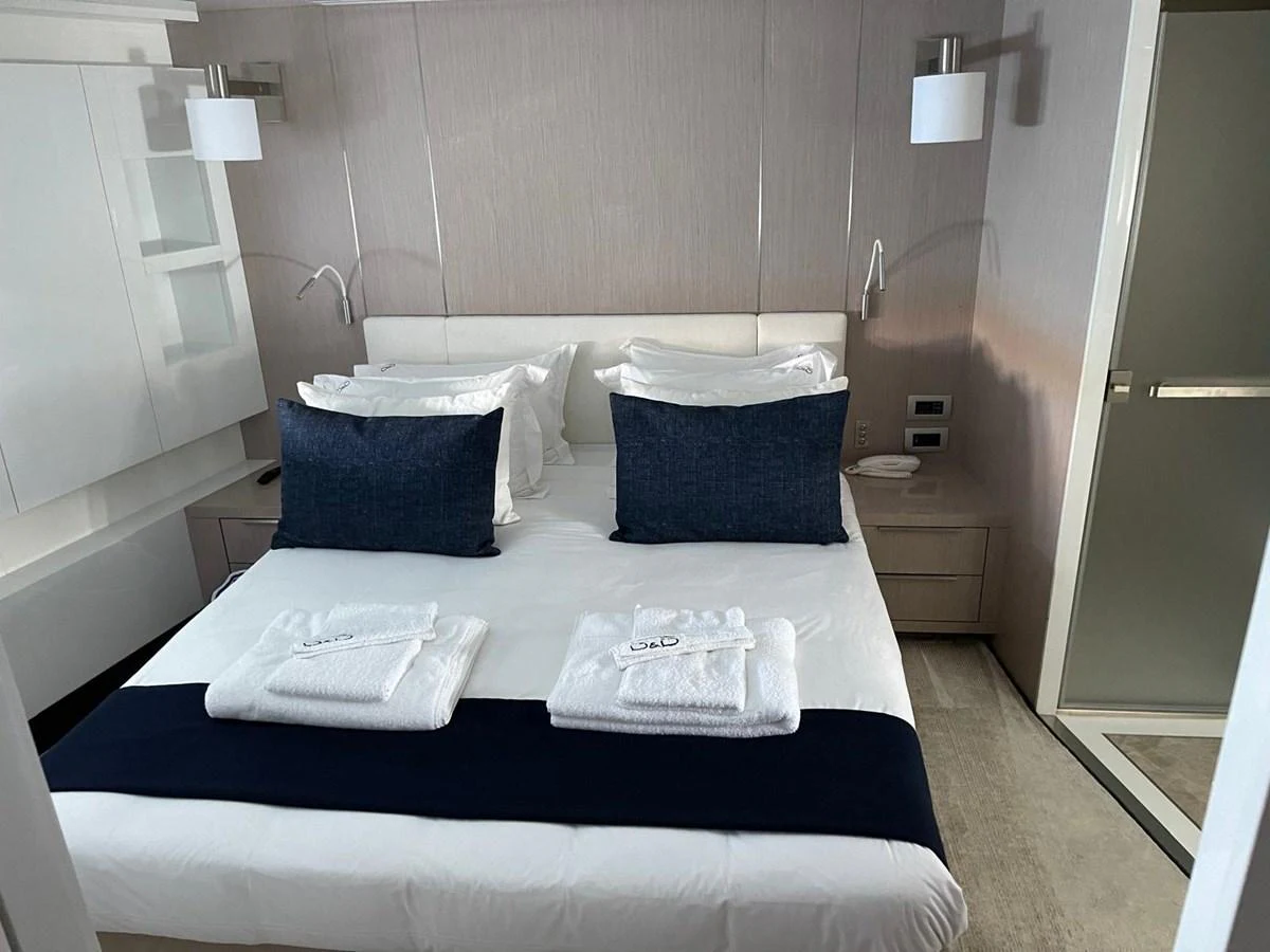 A cozy stateroom featuring a neatly made bed with plush pillows and fresh towels. aboard D&D Yacht for Sale