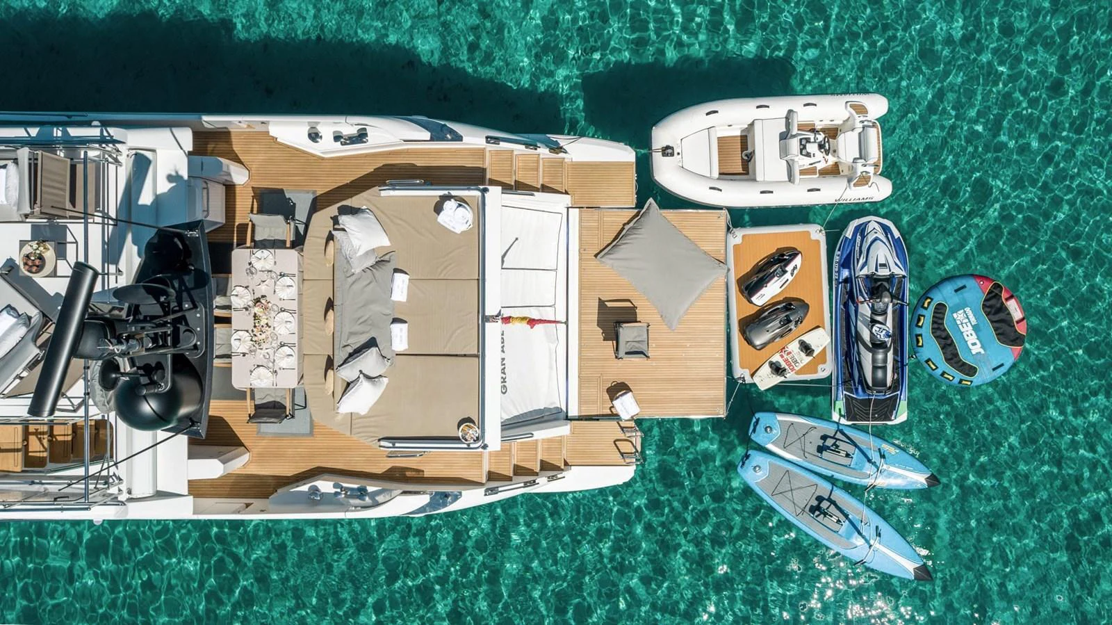 The aft deck of the yacht is beautifully set up with lounging areas and water toys, perfect for enjoying the clear blue waters. aboard GRAN ABE II Yacht for Sale