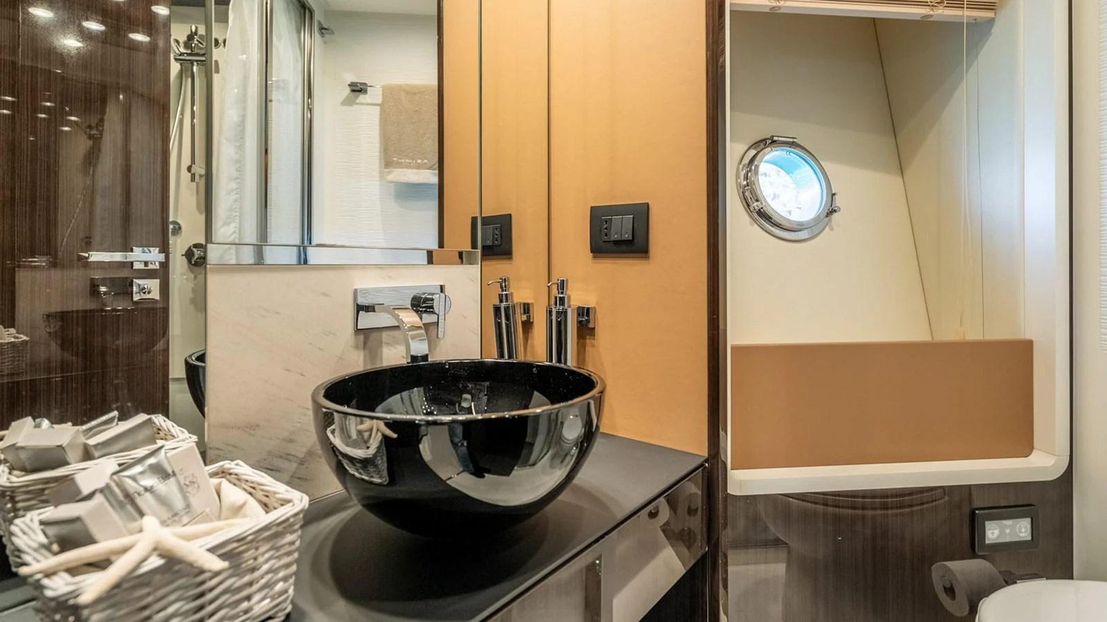A modern yacht bathroom featuring a sleek black sink and a small porthole window. aboard GRAN ABE II Yacht for Sale