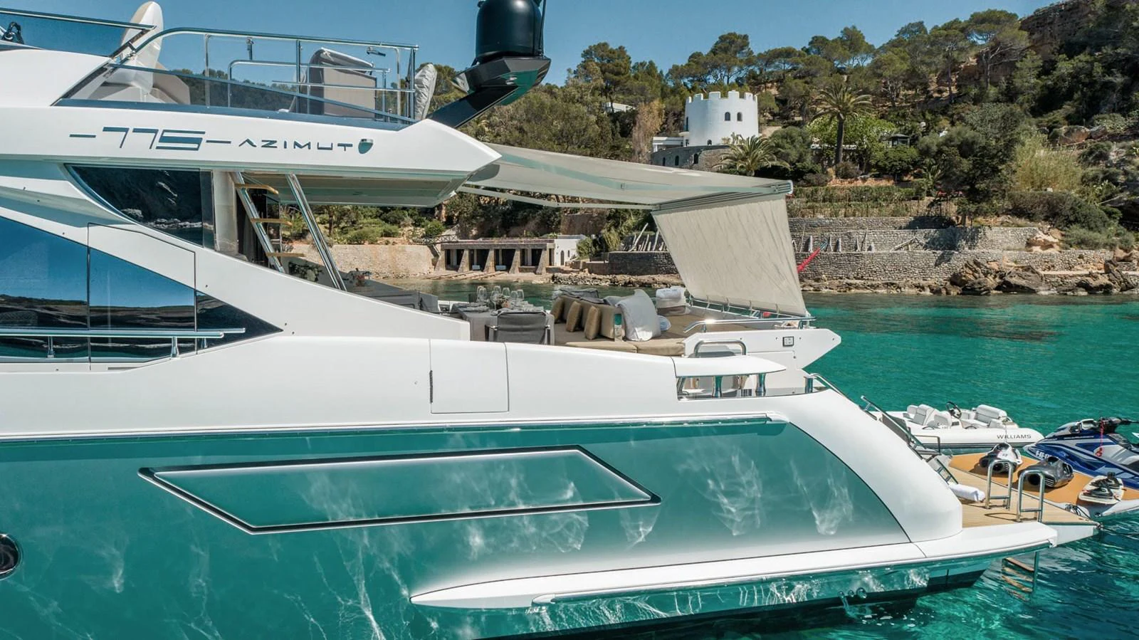 The yacht's aft deck is showcased with a view of the surrounding turquoise waters and lush coastline. aboard GRAN ABE II Yacht for Sale