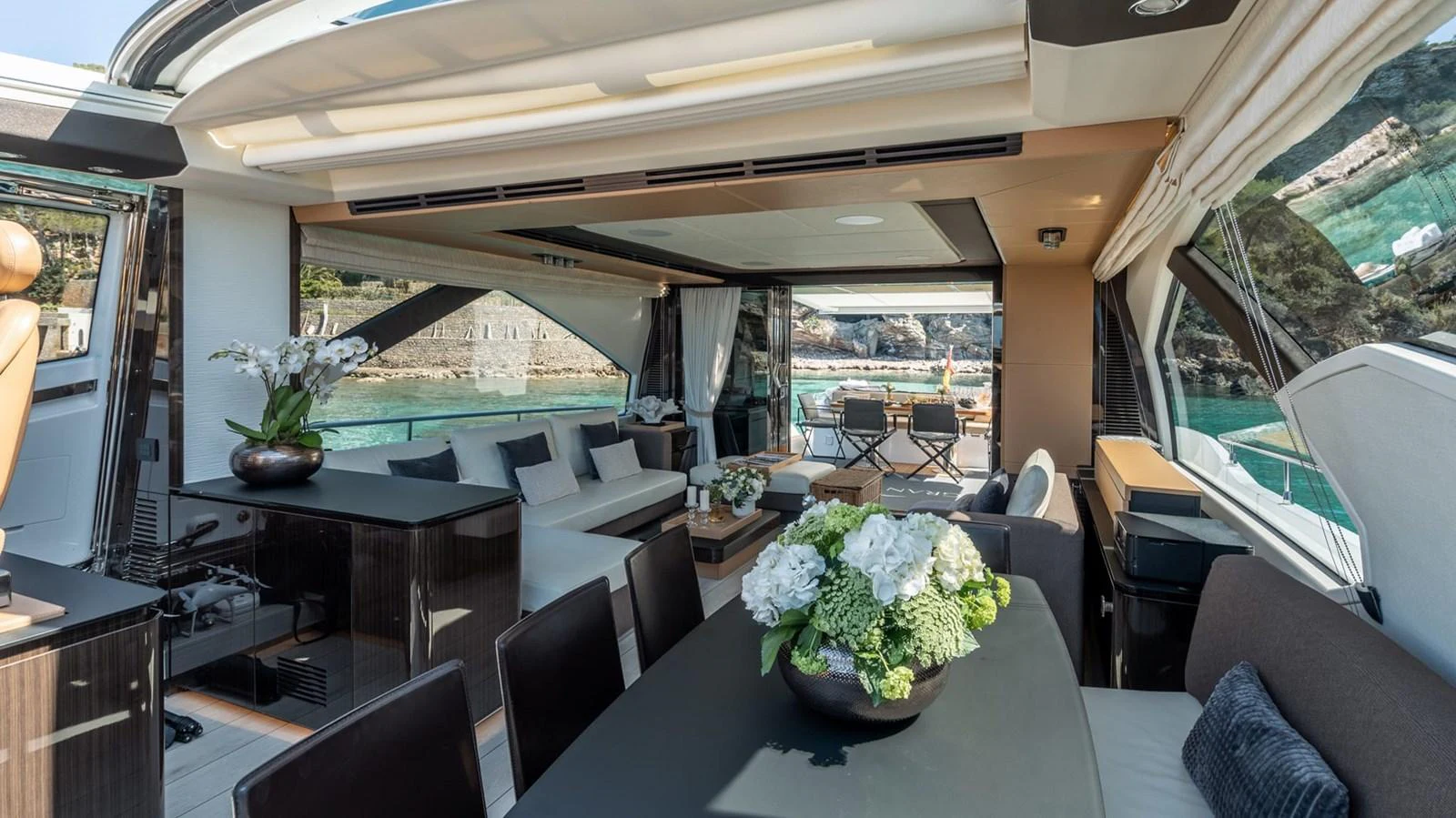 The spacious salon features elegant seating and dining areas with large windows offering stunning views. aboard GRAN ABE II Yacht for Sale