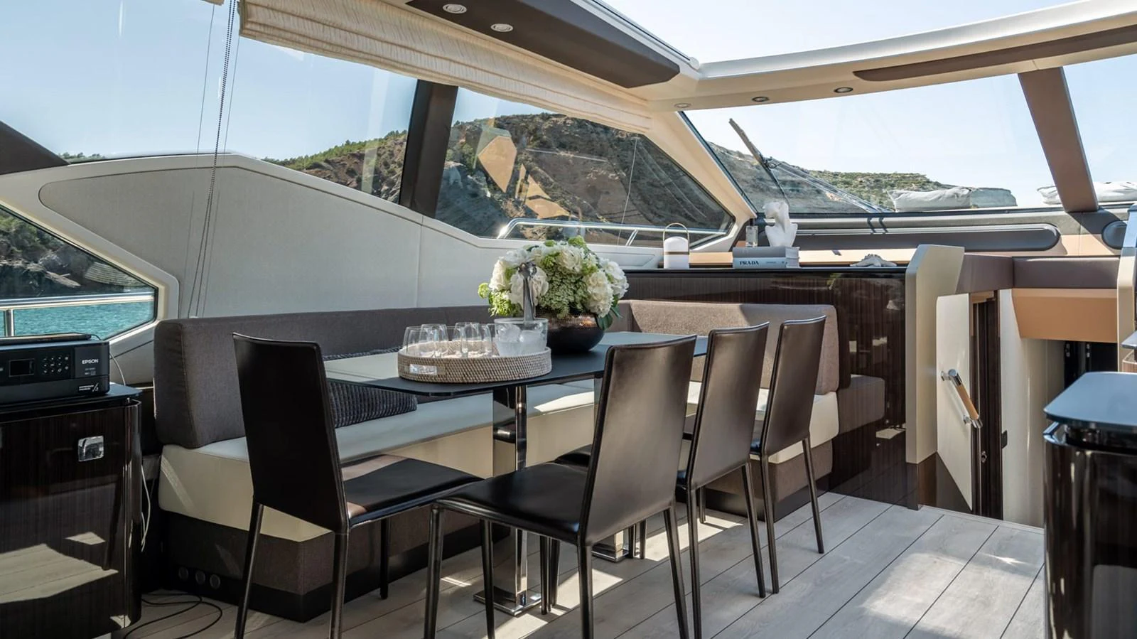 The yacht's dining area features a sleek table with modern chairs, set against large windows offering scenic views. aboard GRAN ABE II Yacht for Sale