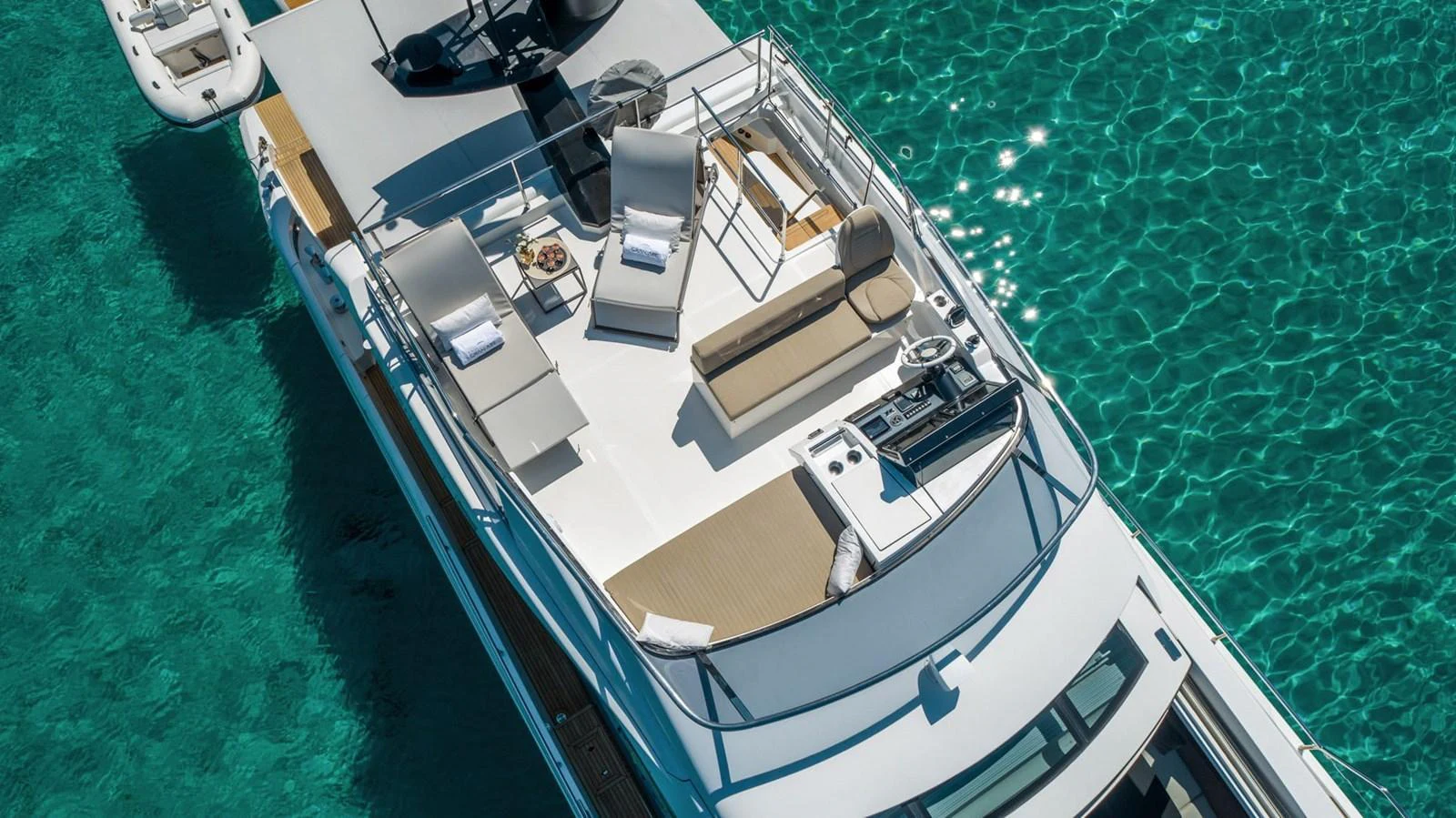 The yacht's sundeck offers a luxurious space for relaxation with sun loungers and a stunning view of the clear turquoise water. aboard GRAN ABE II Yacht for Sale