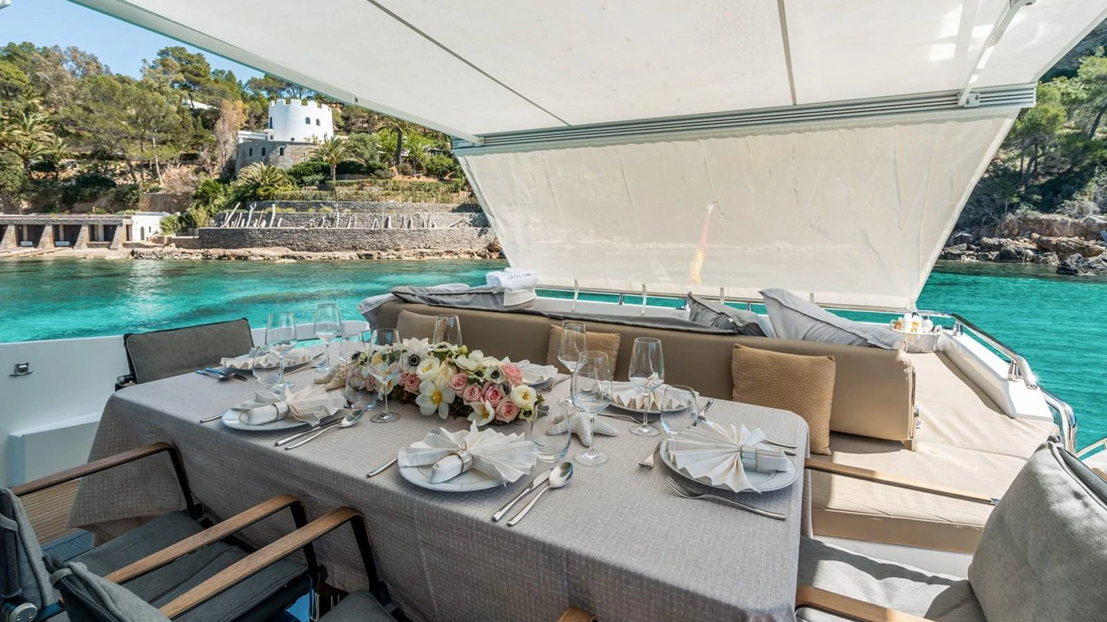 The yacht features an elegant alfresco dining area with a beautifully set table, perfect for enjoying meals with a stunning view of the water. aboard GRAN ABE II Yacht for Sale