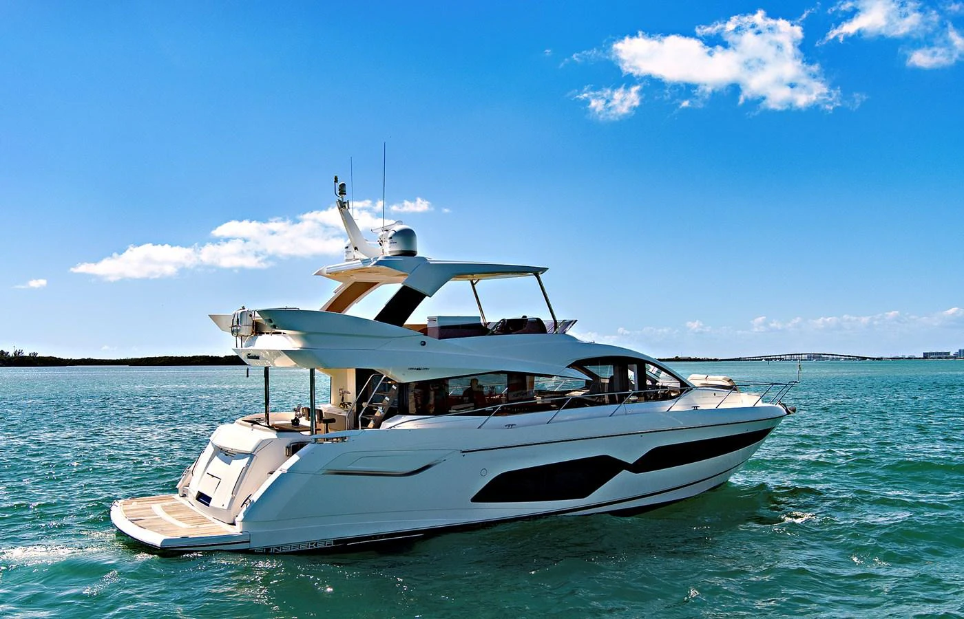 A sleek and modern yacht cruising on a sunny day with clear blue skies. aboard SMITTEN Yacht for Sale