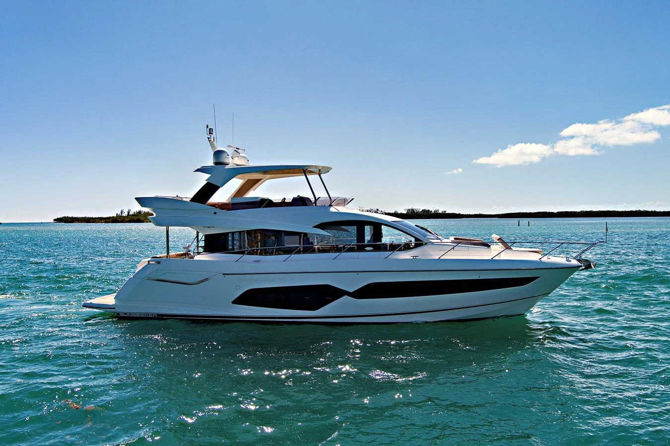 A sleek and modern yacht cruising on calm waters under a clear blue sky. aboard SMITTEN Yacht for Sale