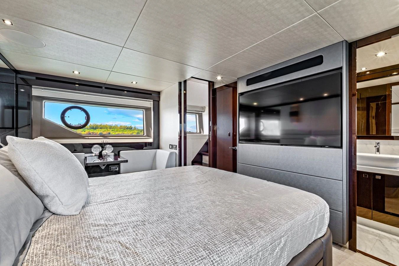 A luxurious stateroom featuring a large bed, flat-screen TV, and an ensuite bathroom with modern amenities. aboard SMITTEN Yacht for Sale