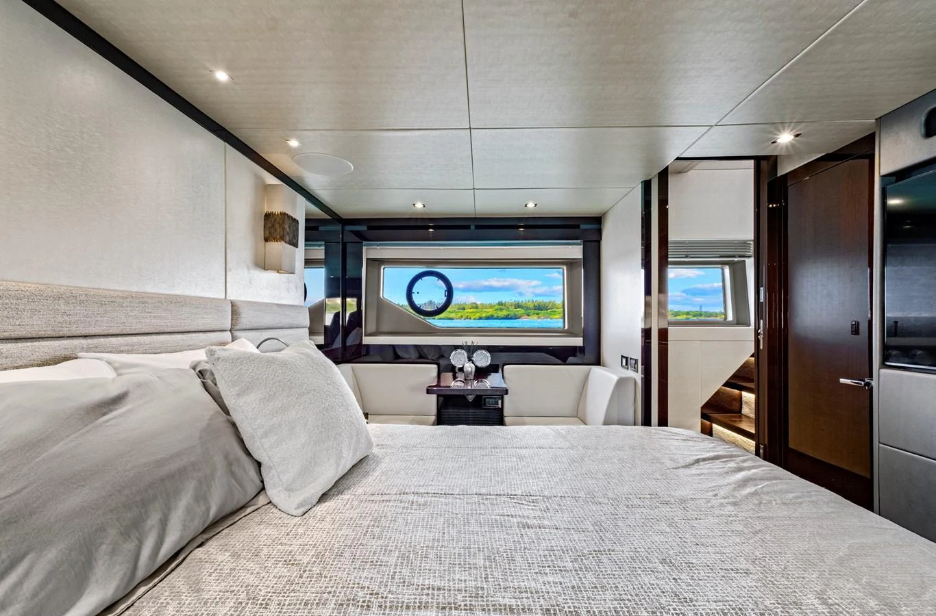 A luxurious stateroom featuring a large bed, elegant decor, and a scenic view through the window. aboard SMITTEN Yacht for Sale