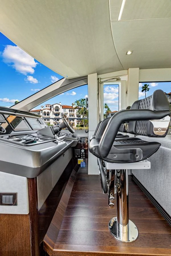 The helm station features modern controls and comfortable seating with a view of the surroundings. aboard SMITTEN Yacht for Sale