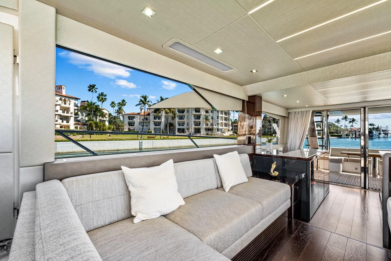 The salon features a spacious seating area with large windows offering stunning waterfront views. aboard SMITTEN Yacht for Sale