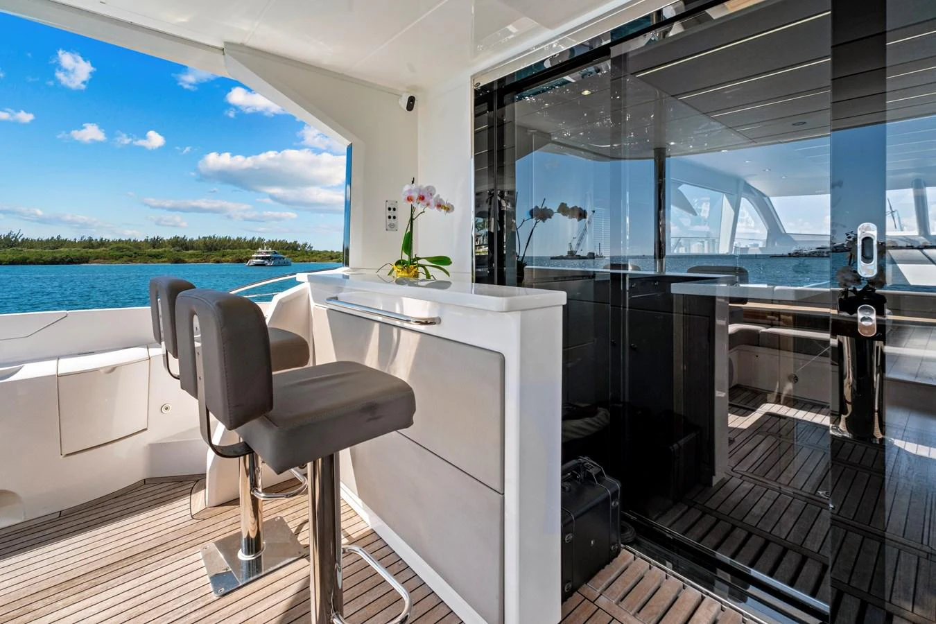 The aft deck features a sleek bar area with modern seating and a view of the serene waters. aboard SMITTEN Yacht for Sale