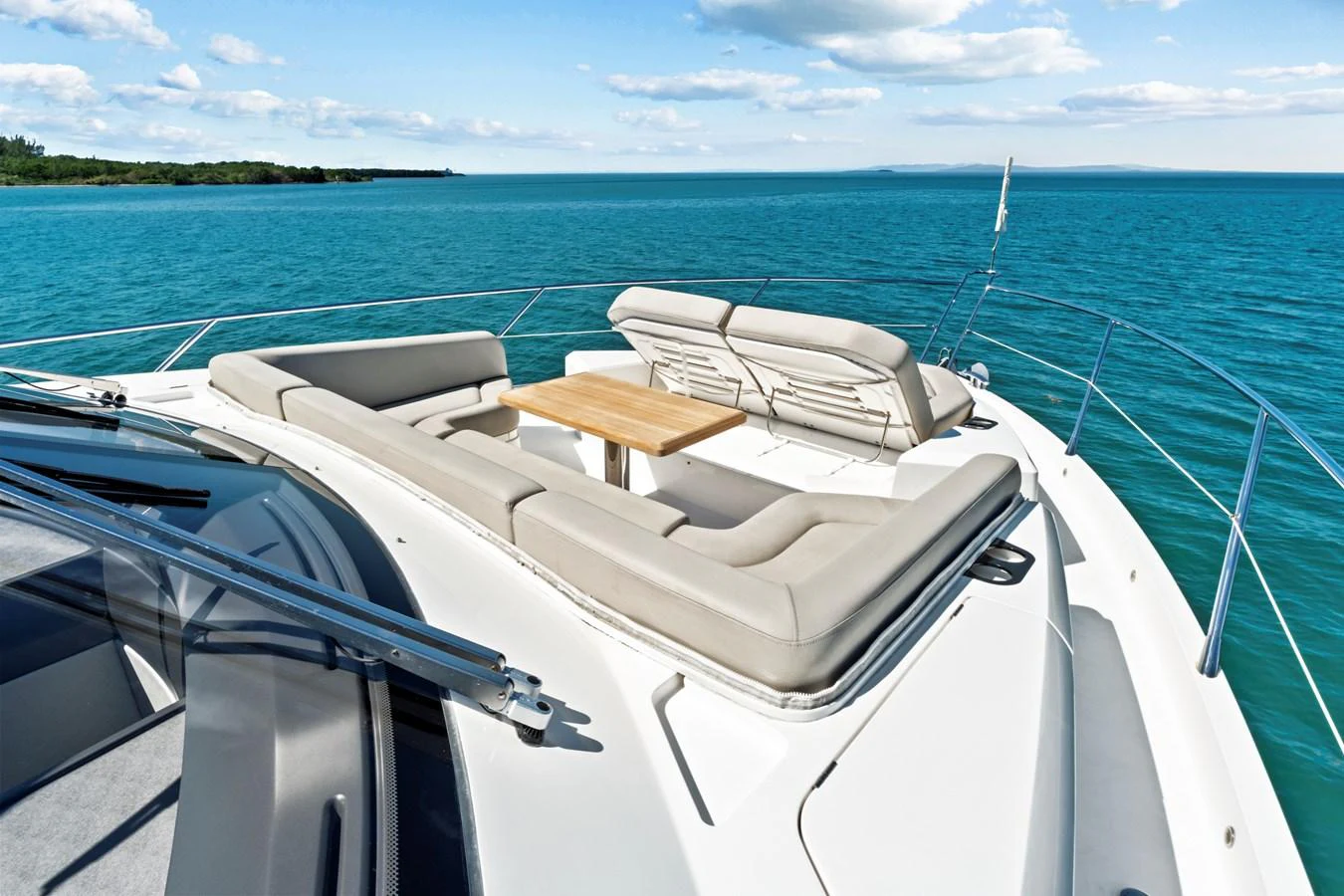 The foredeck features a luxurious sunbathing area with plush seating and a central table, offering stunning ocean views. aboard SMITTEN Yacht for Sale