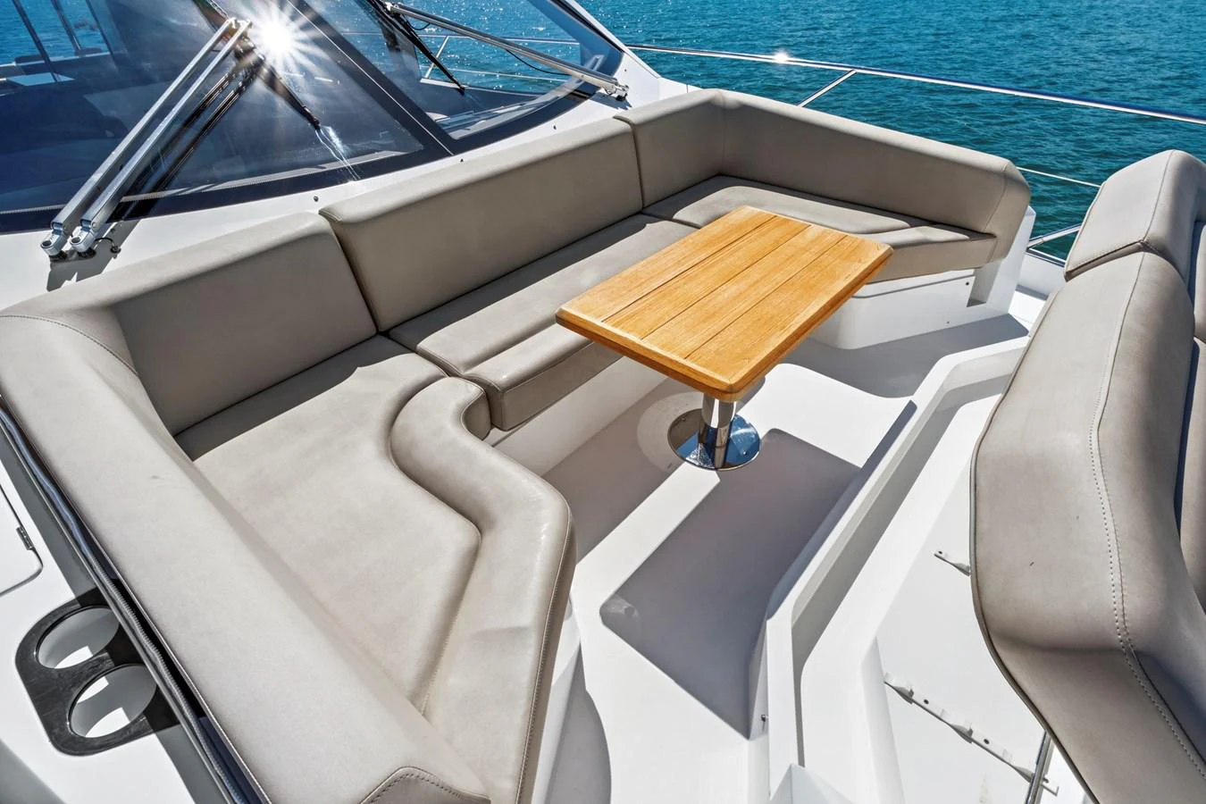 The yacht features a comfortable and stylish outdoor seating area with a wooden table, perfect for relaxing and enjoying the view. aboard SMITTEN Yacht for Sale