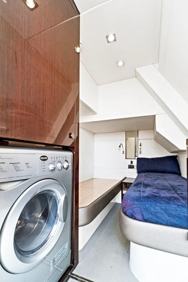 The crew quarters feature a compact yet functional layout with a washing machine and a cozy sleeping area. aboard SMITTEN Yacht for Sale