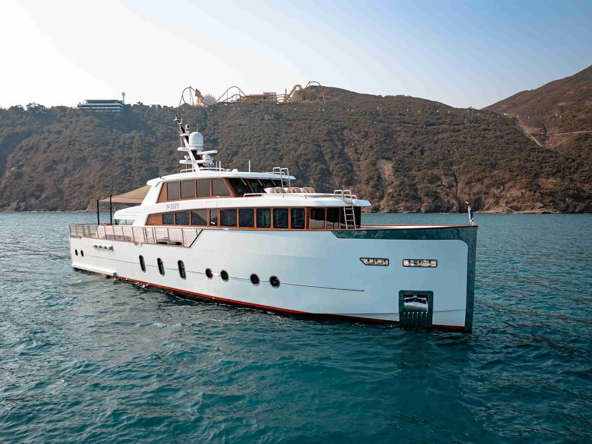 A sleek and modern yacht cruising in clear blue waters with a scenic coastal backdrop. aboard VERO Yacht for Sale