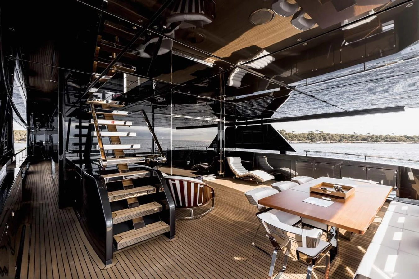 The aft deck features a luxurious seating area with a dining table and a staircase leading to the upper deck. aboard LADY FIRST Yacht for Sale