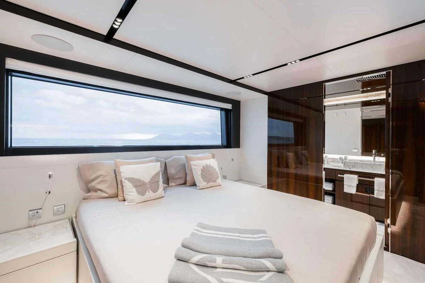 The stateroom features a luxurious bed with a view of the sea through a large window. aboard LADY FIRST Yacht for Sale