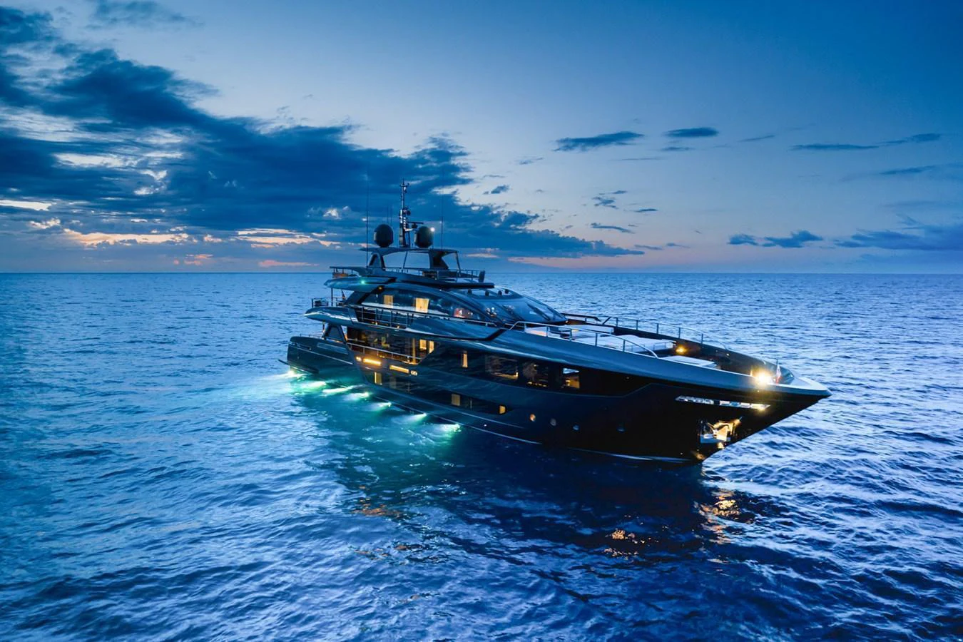 A sleek yacht illuminated against a twilight sky, cruising through calm waters. aboard LADY FIRST Yacht for Sale