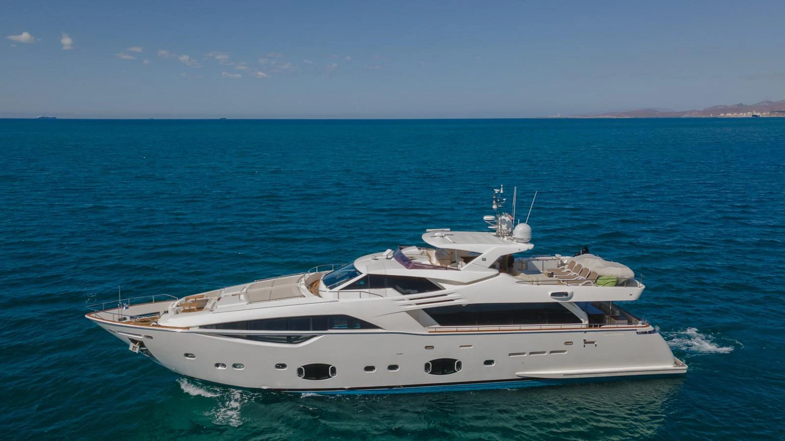 A luxurious yacht cruises through clear blue waters under a bright sky. aboard AMORE MIO Yacht for Sale