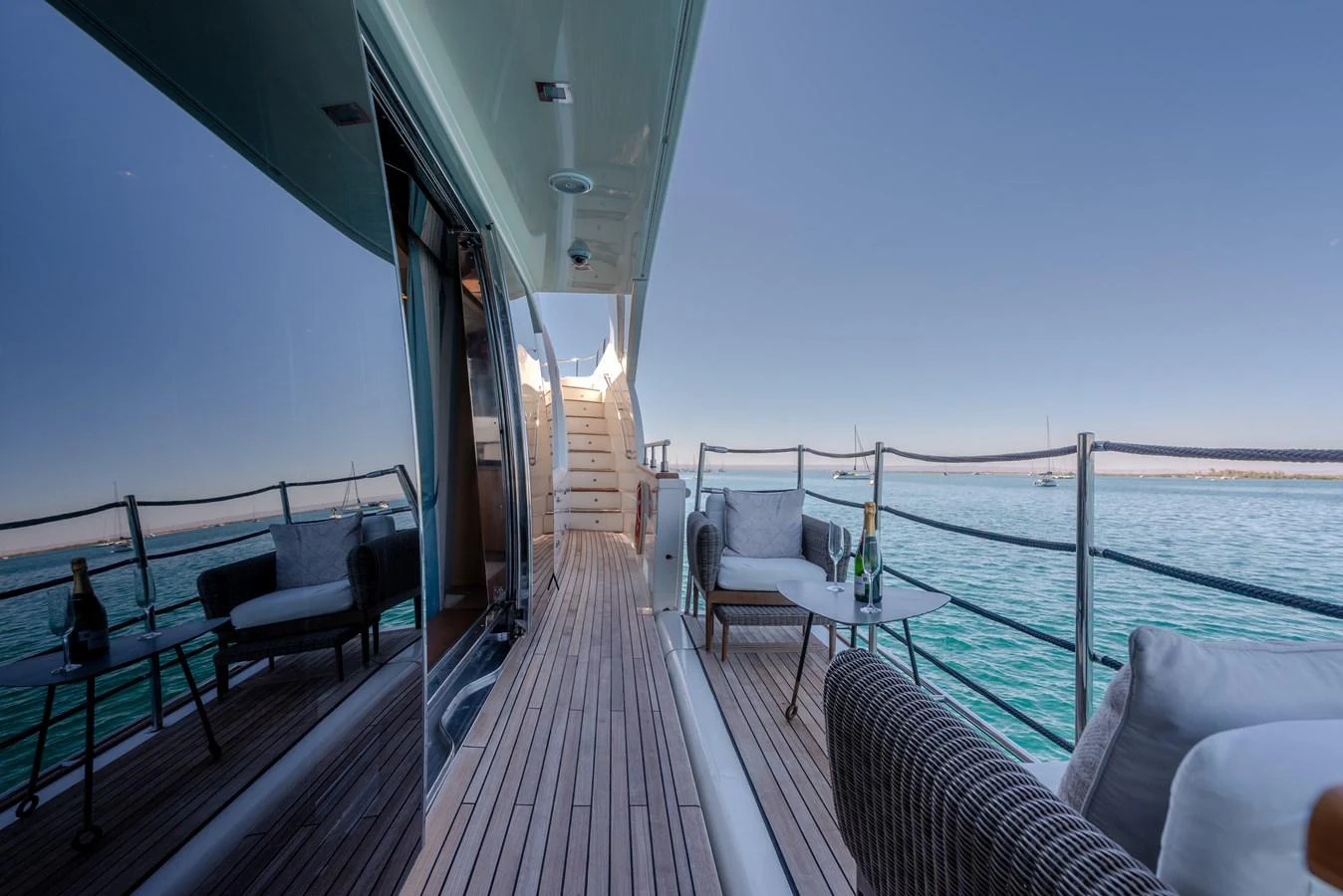 The side deck offers a serene view of the water with comfortable seating and a table for relaxation. aboard AMORE MIO Yacht for Sale