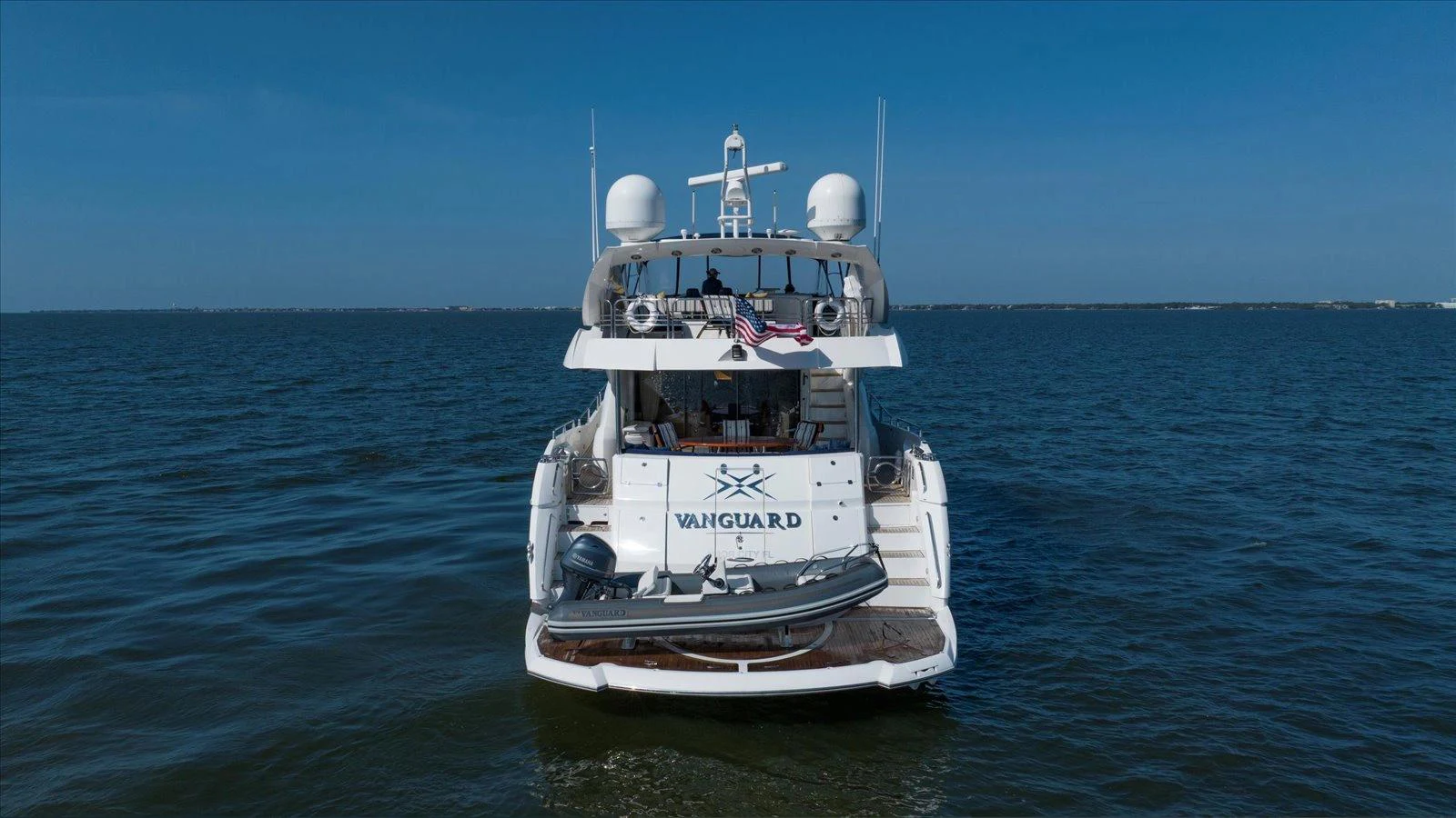 The yacht is seen from the rear, showcasing its spacious deck and water toys. aboard VANGUARD Yacht for Sale