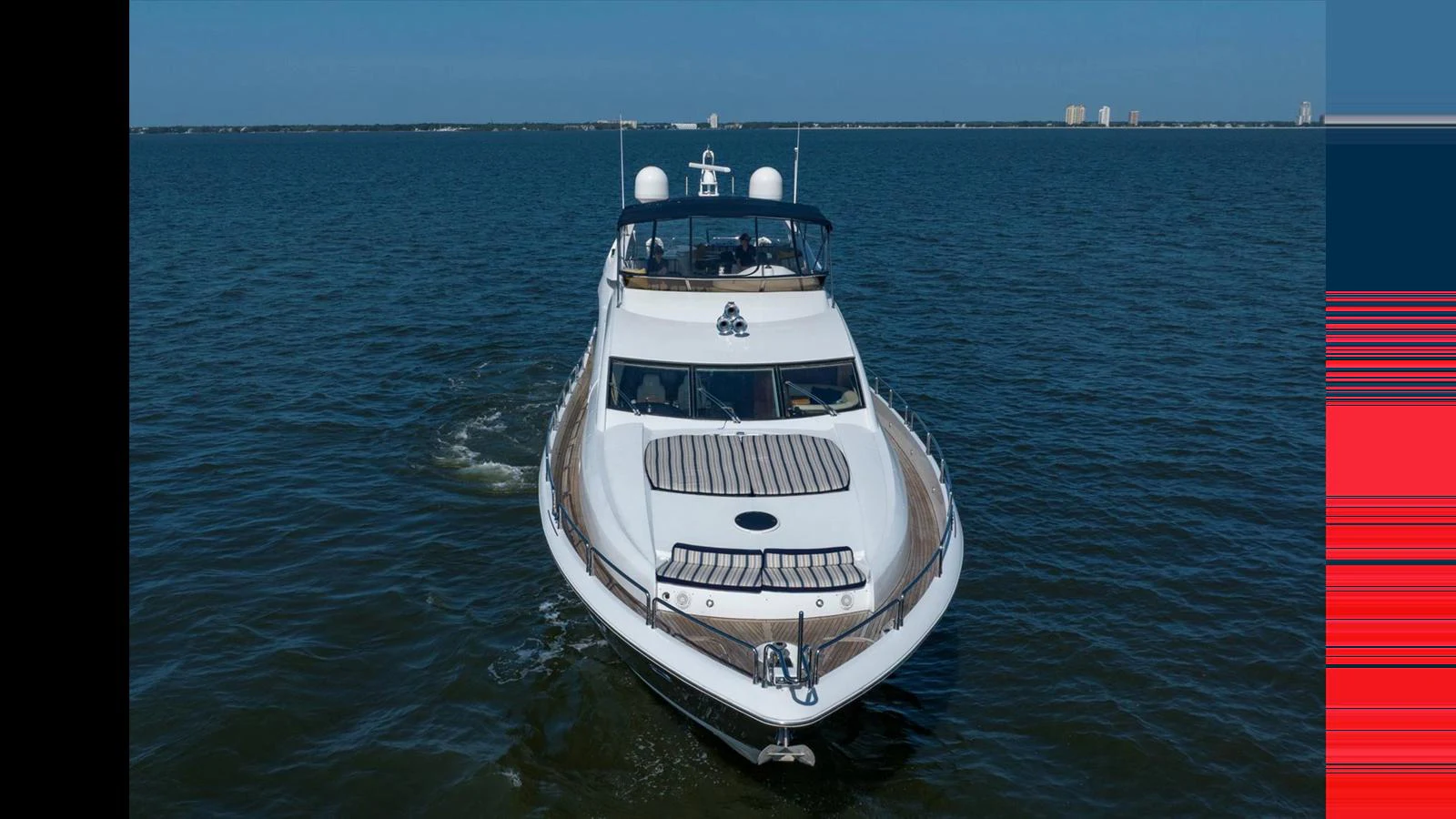 A sleek yacht cruising on calm waters under a clear blue sky. aboard VANGUARD Yacht for Sale
