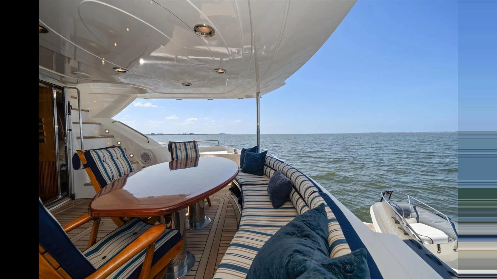 The aft deck features a spacious seating area with a polished wooden table, perfect for alfresco dining while enjoying the sea view. aboard VANGUARD Yacht for Sale