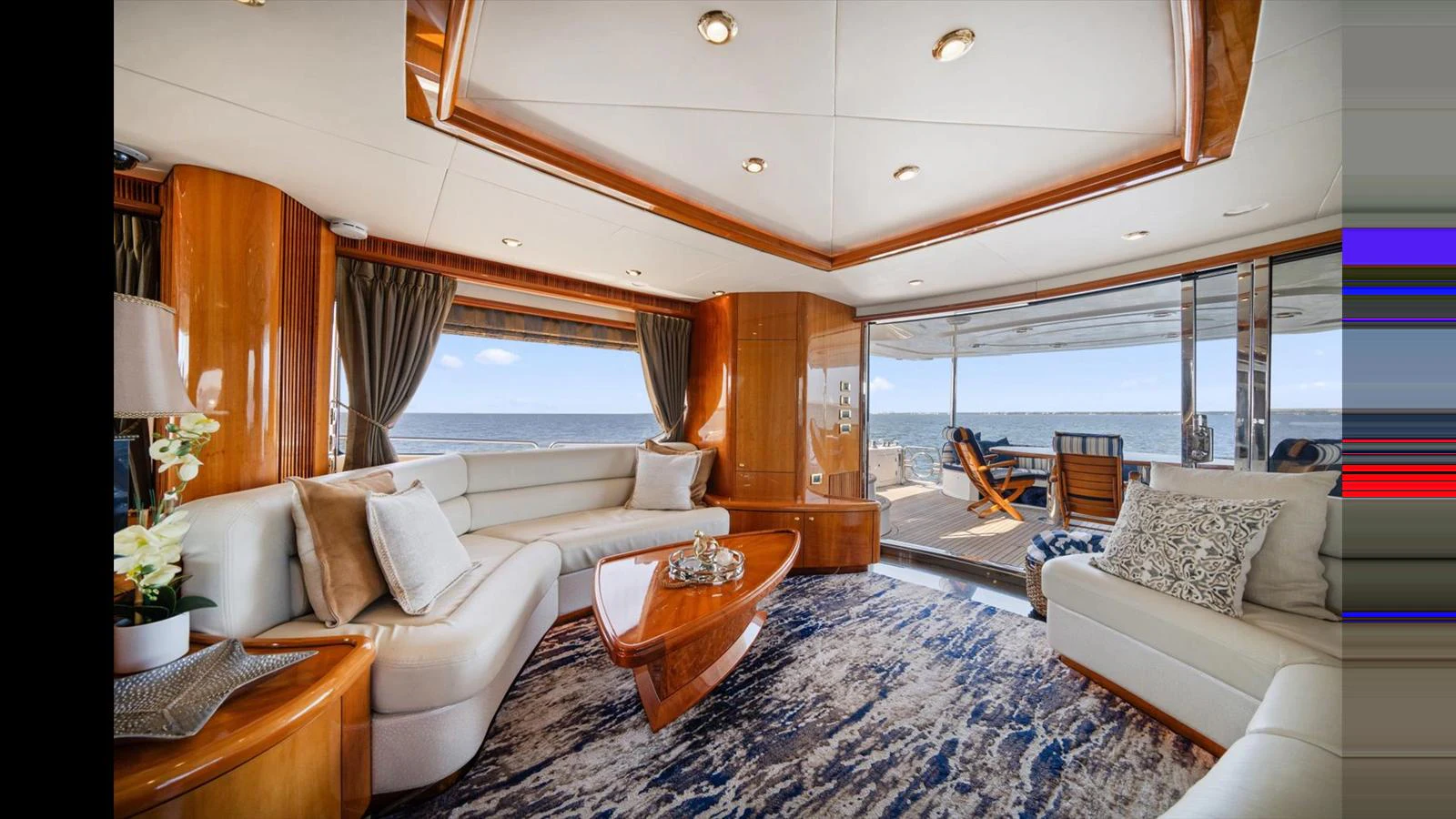 The yacht's salon features luxurious seating, elegant wood finishes, and expansive windows offering stunning ocean views. aboard VANGUARD Yacht for Sale