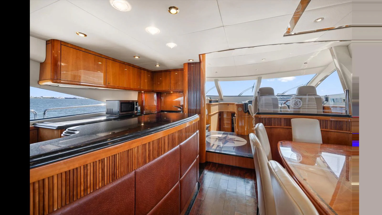 The yacht's galley features elegant wood cabinetry and a spacious dining area with a view of the helm. aboard VANGUARD Yacht for Sale