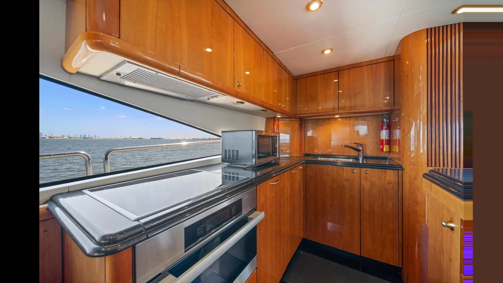 The galley features sleek wooden cabinetry and modern appliances with a view of the water. aboard VANGUARD Yacht for Sale