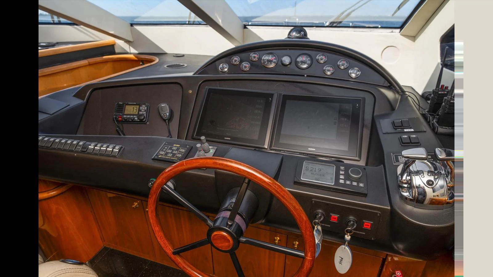 The helm station features advanced navigation equipment and a stylish wooden steering wheel. aboard VANGUARD Yacht for Sale