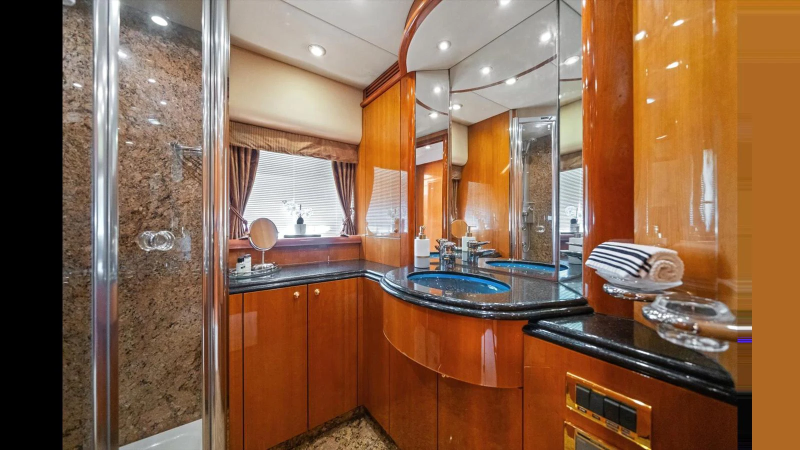 The yacht's bathroom features luxurious wood cabinetry, a sleek black countertop, and a spacious shower area. aboard VANGUARD Yacht for Sale