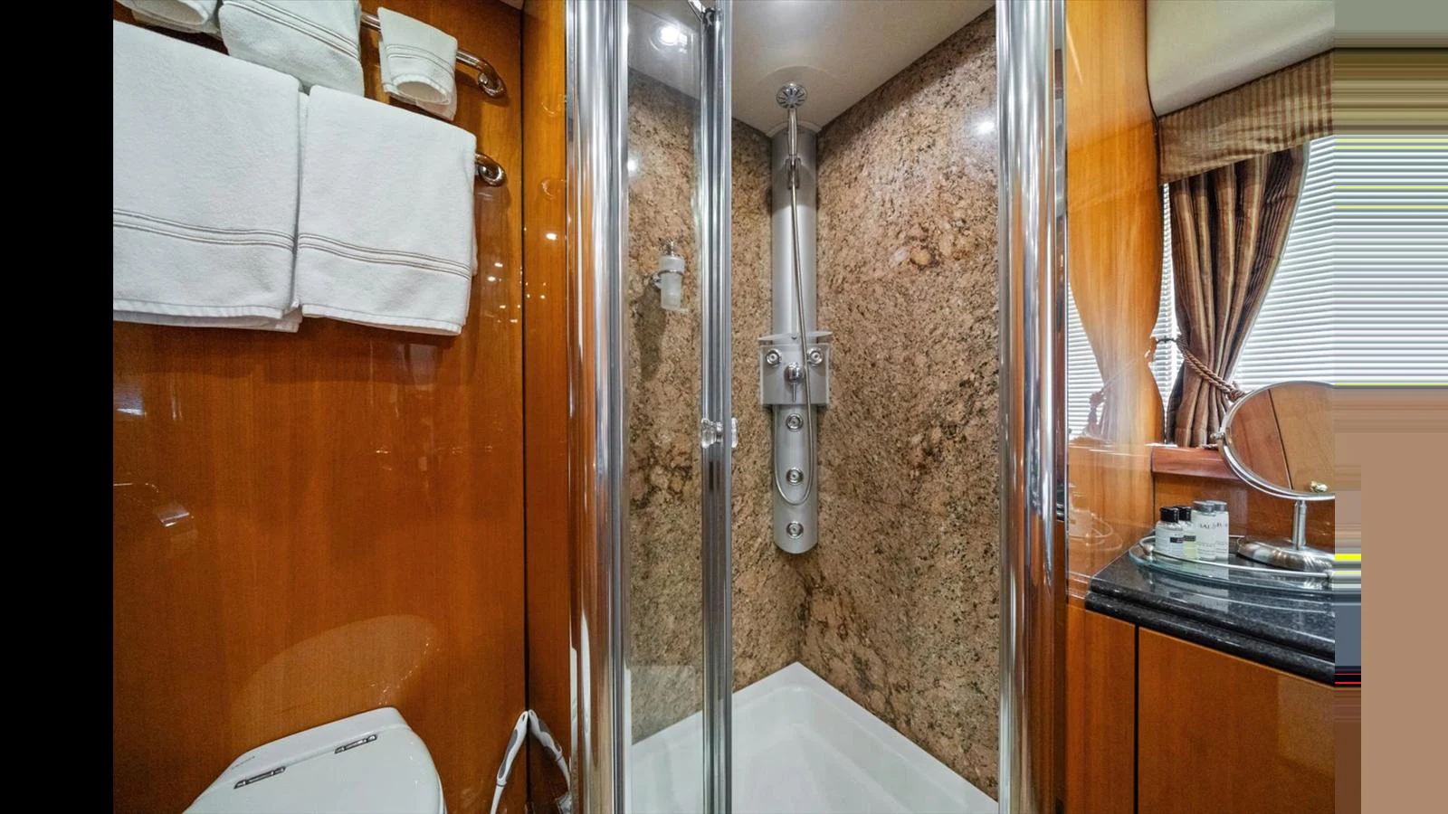 The yacht's bathroom features a modern shower with elegant wood and marble finishes. aboard VANGUARD Yacht for Sale