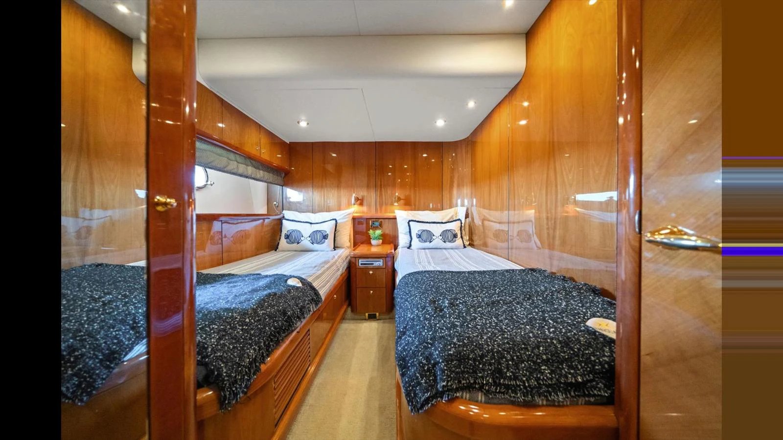 The twin stateroom features two comfortable beds with luxurious bedding and warm wooden finishes. aboard VANGUARD Yacht for Sale