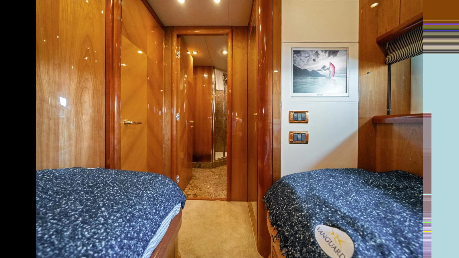 The guest cabin features twin beds with luxurious bedding and warm wood finishes. aboard VANGUARD Yacht for Sale