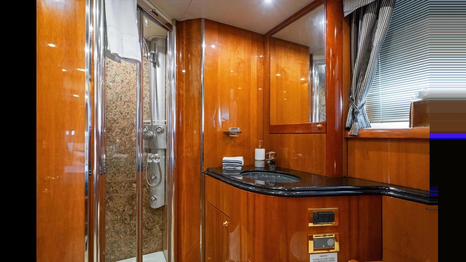 The yacht's bathroom features luxurious wood paneling and a modern shower. aboard VANGUARD Yacht for Sale