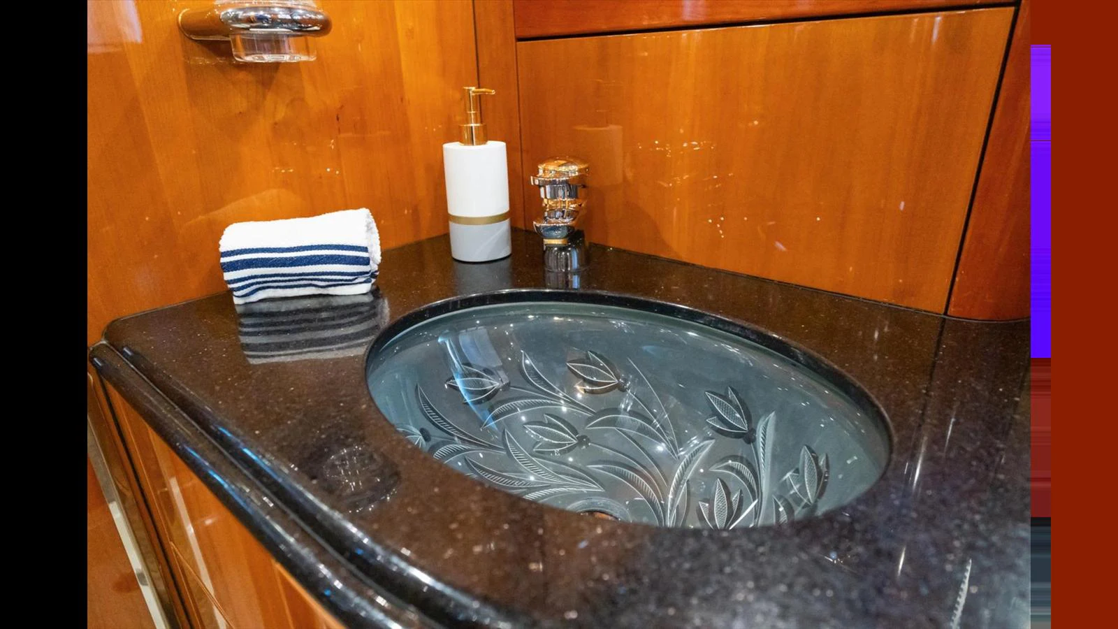 The yacht's bathroom features a stylish glass sink with intricate designs and a sleek countertop. aboard VANGUARD Yacht for Sale